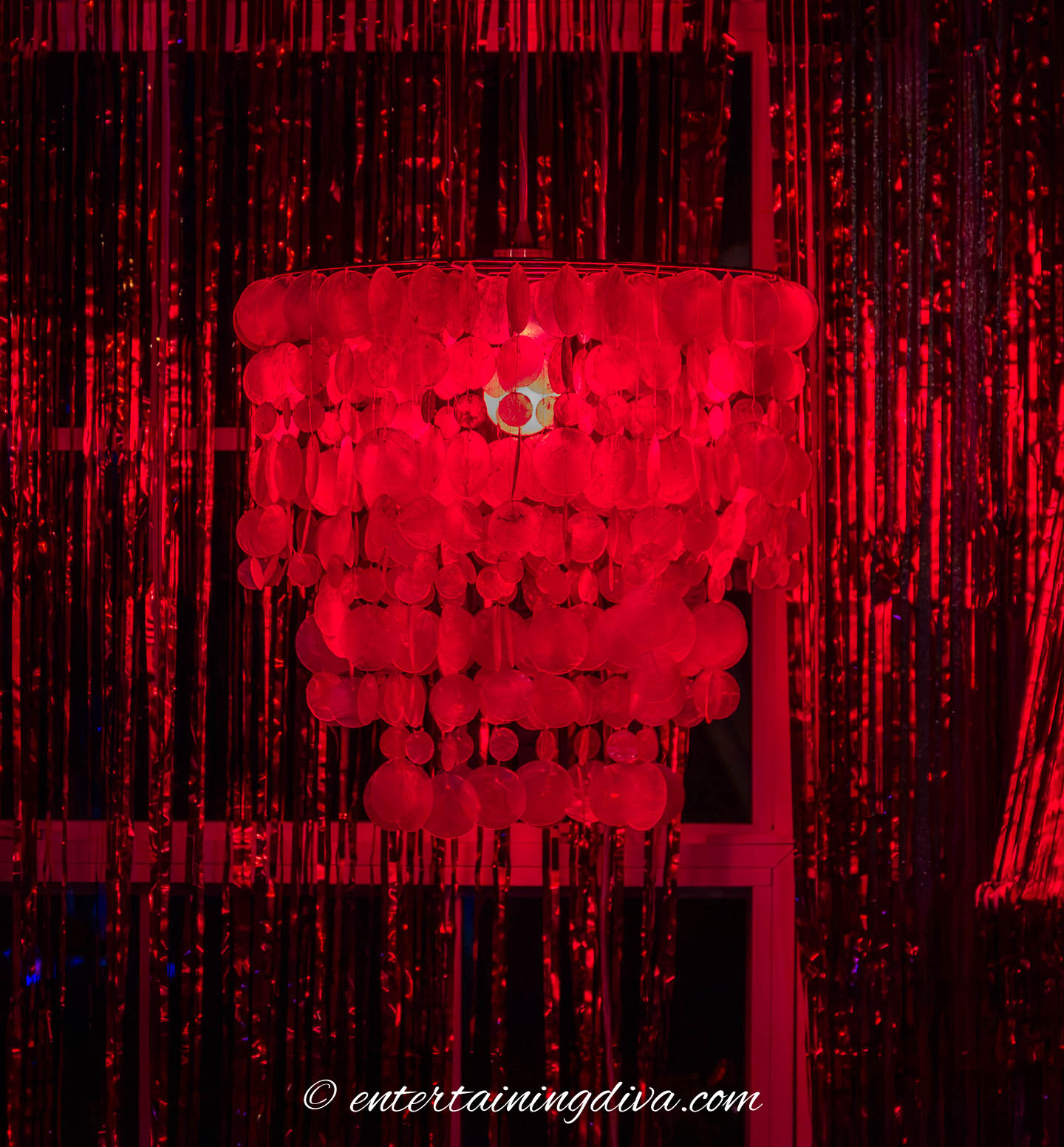 A hanging light fixture with a red light bulb in it.