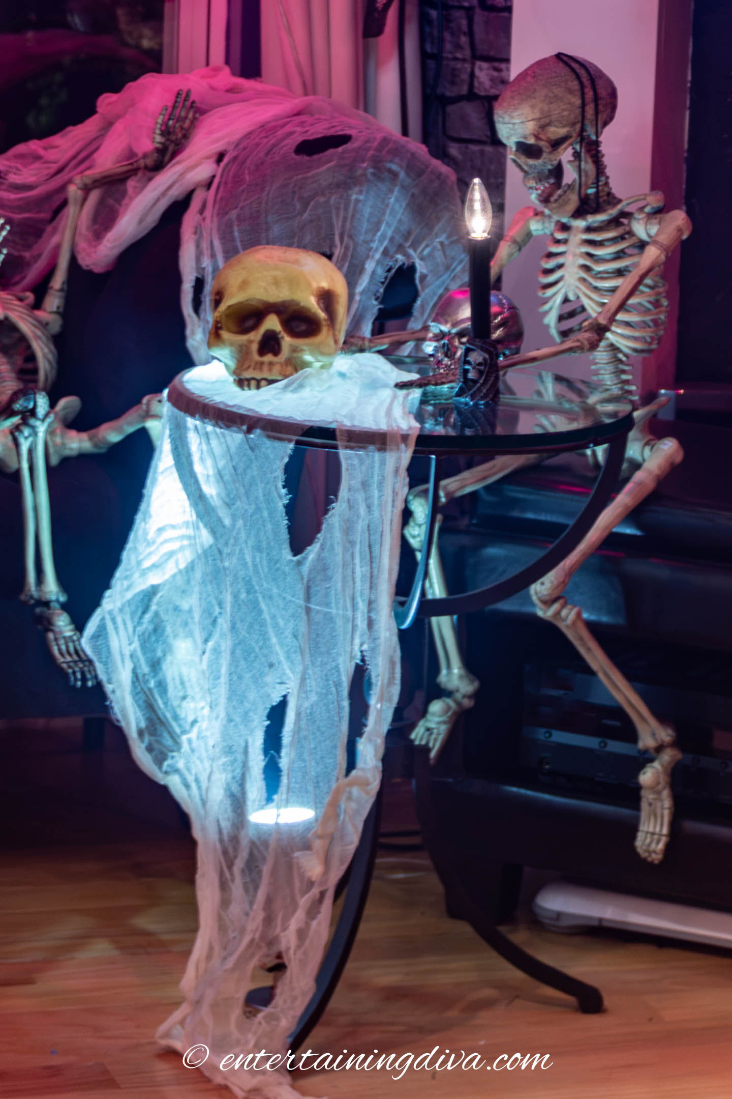 Uplighting under a glass table with white creepy cloth and a skull on top