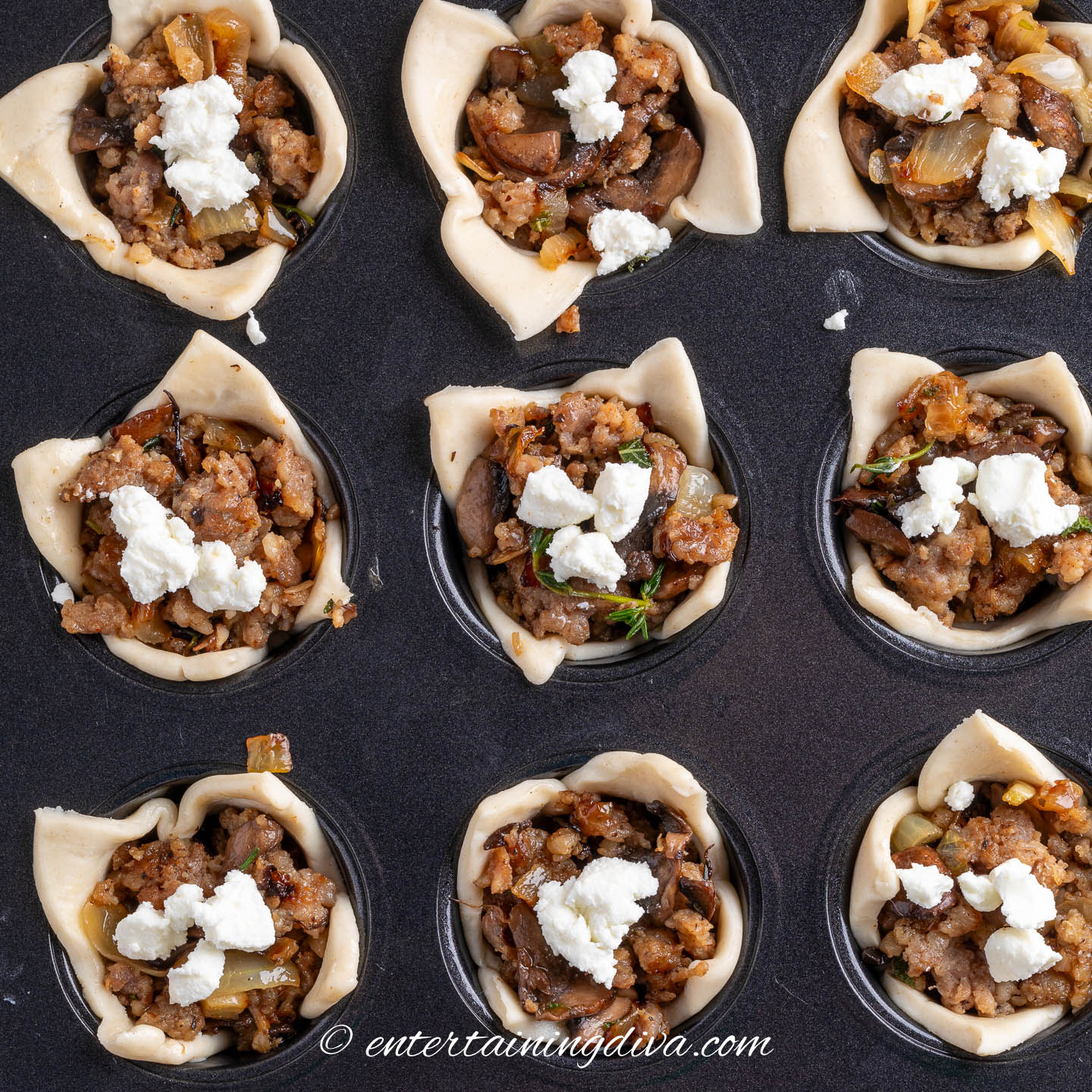 overhead view of mushroom sausage puff pastry bites in a muffin tin before baking