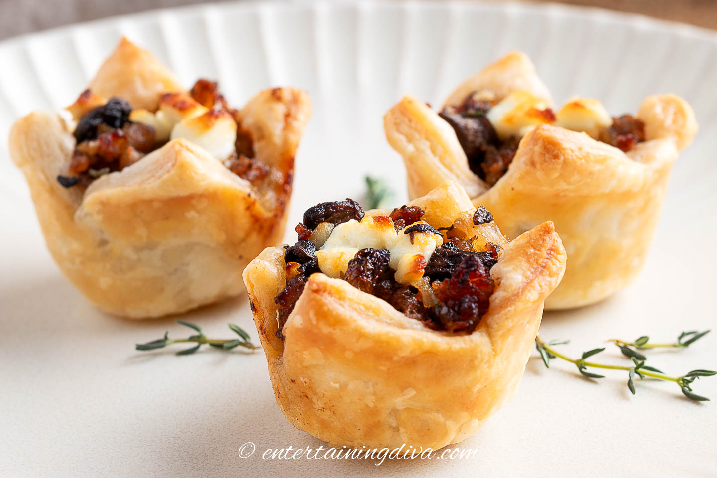 Three mushroom sausage puff pastry bites on a plate