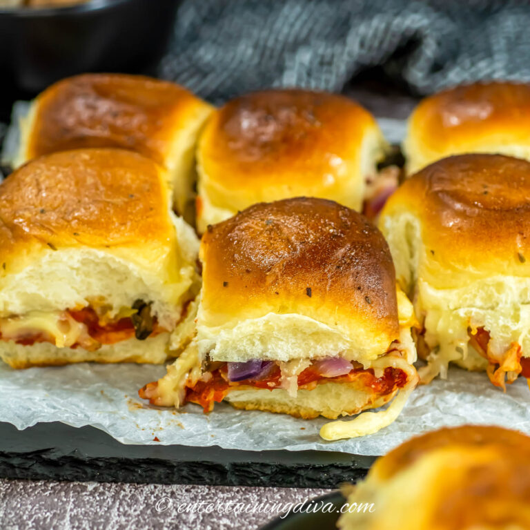 Baked pizza sliders on a parchment-covered black tray