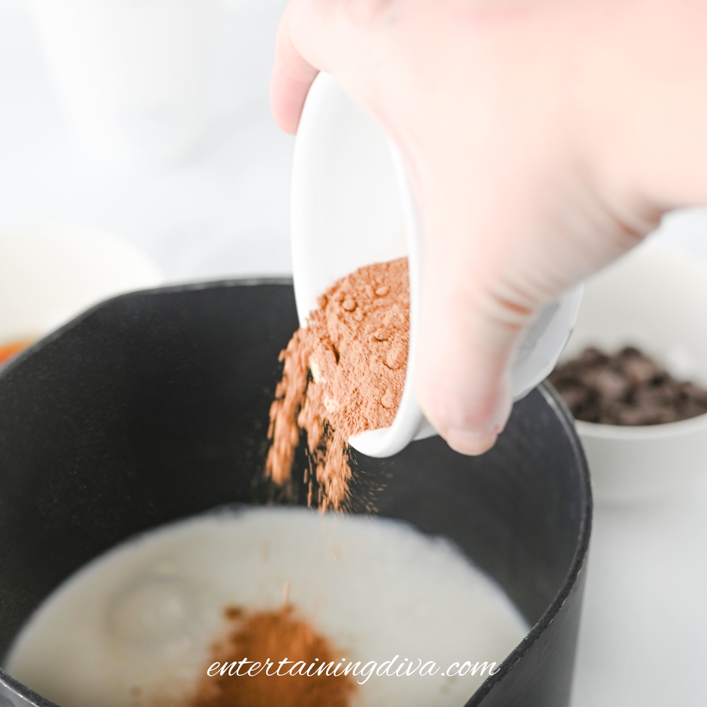 Cocoa Powder being poured into a pot with milk