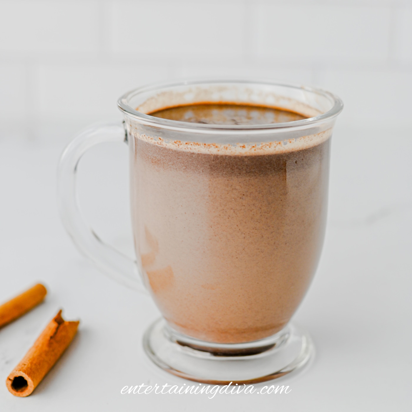 Hot chocolate poured into a clear glass mug