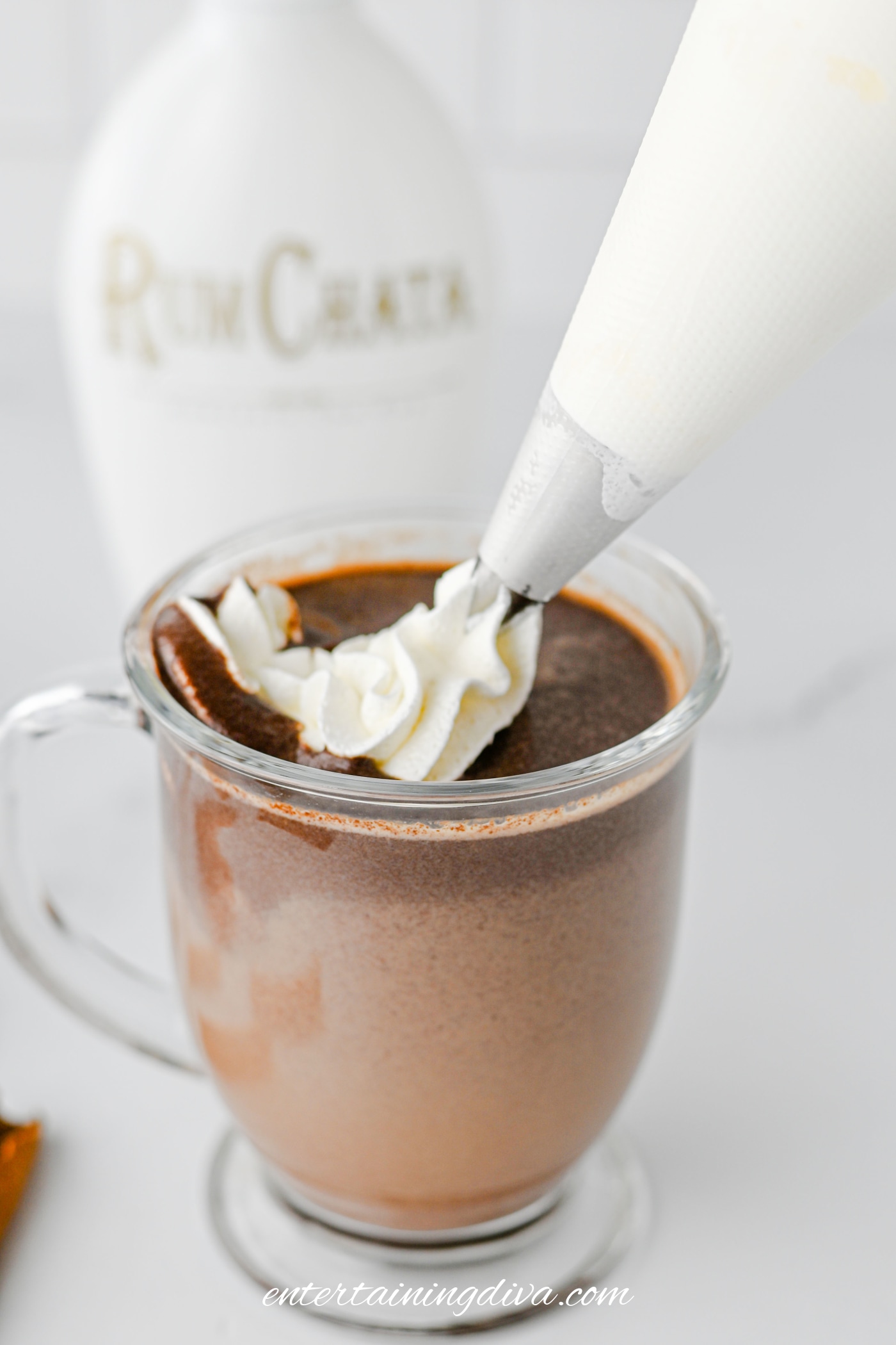 Whipped cream being piped onto hot chocolate