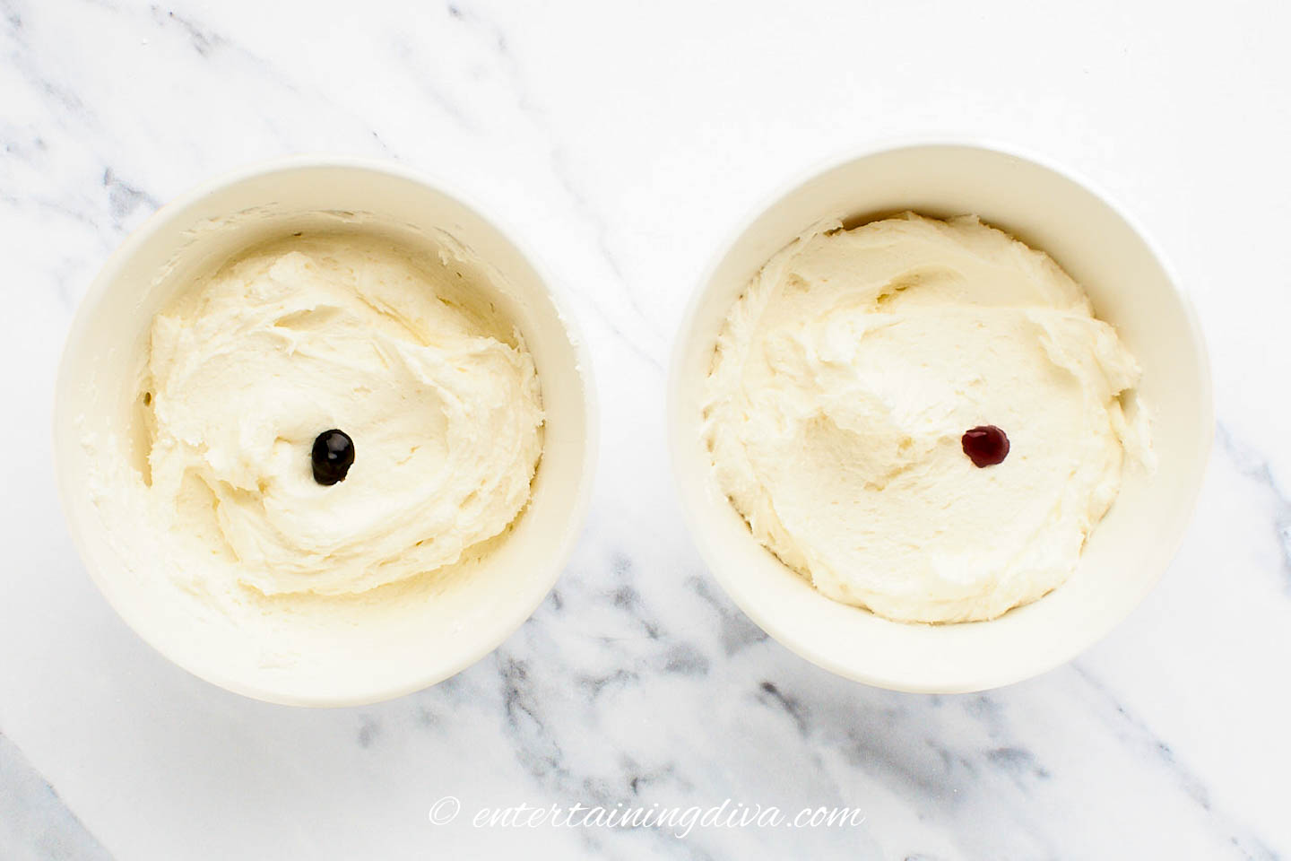 two bowls of white frosting, one with a dot of green food coloring and the other with a dot of red food coloring.