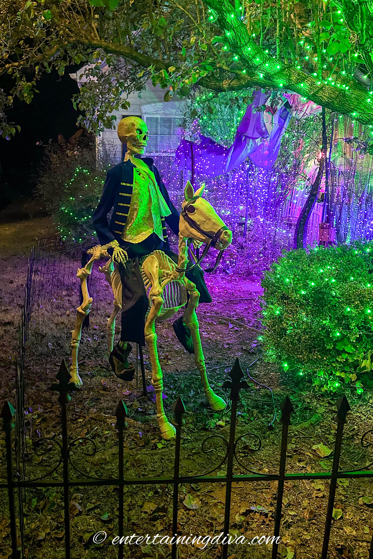 A Fiyero skeleton on a skeleton horse in a Wicked themed outdoor Halloween display at night