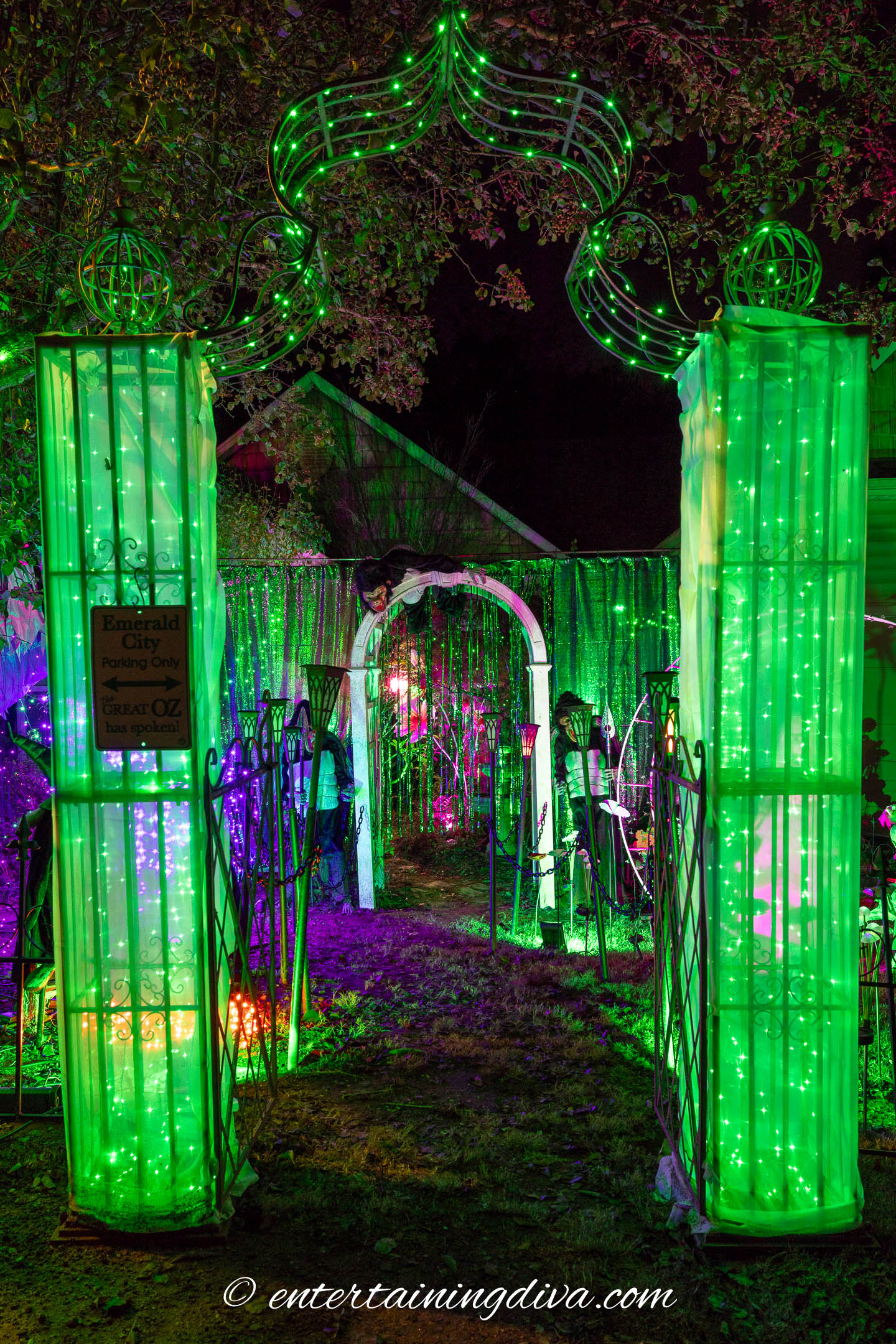 An arbor lit up with green lights for a Halloween light display