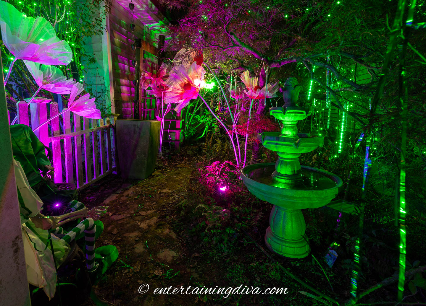 A front courtyard decorated with pink and green lights for a Wicked themed outdoor display