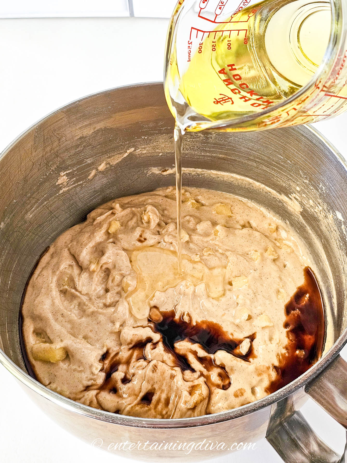 oil being poured into apple cake batter