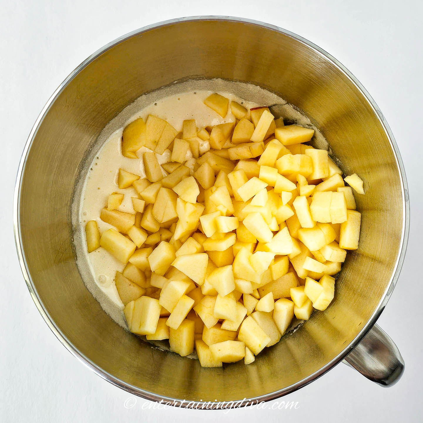 Chopped apples in a mixing bowl with cake batter