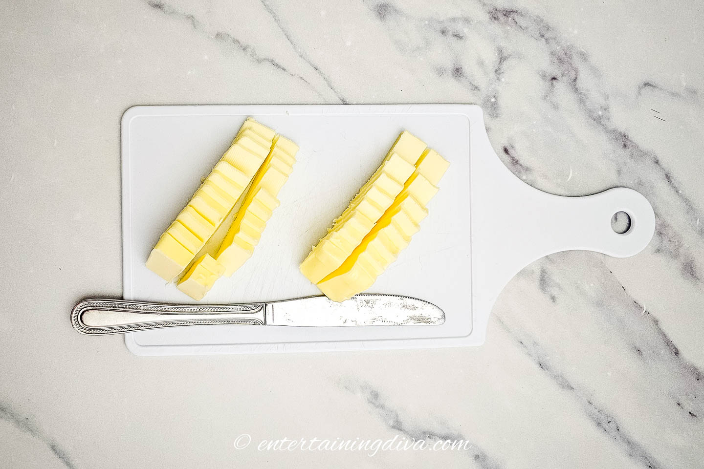 A cutting board with slices of butter and a knife