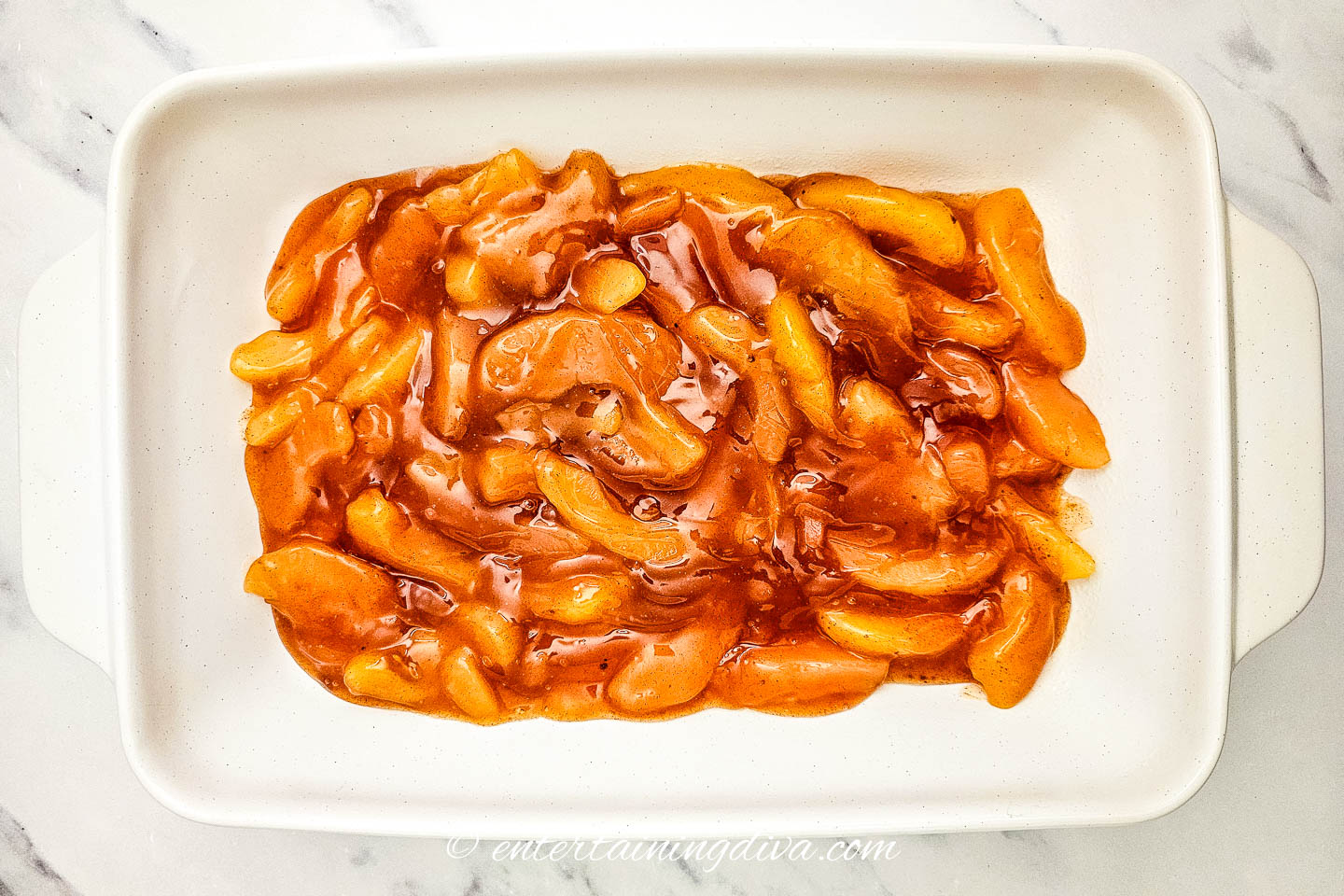 apple pie filling mixture spread across the bottom of a 9x13 baking pan