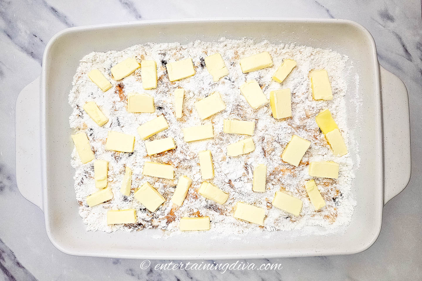 pieces of butter scattered across the top of apple cobbler before cooking