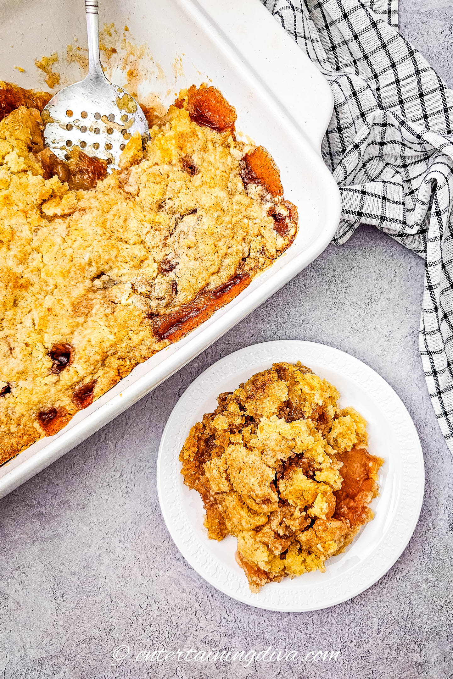 Easy apple cobbler on a small white plate beside a baking dish of apple cobbler