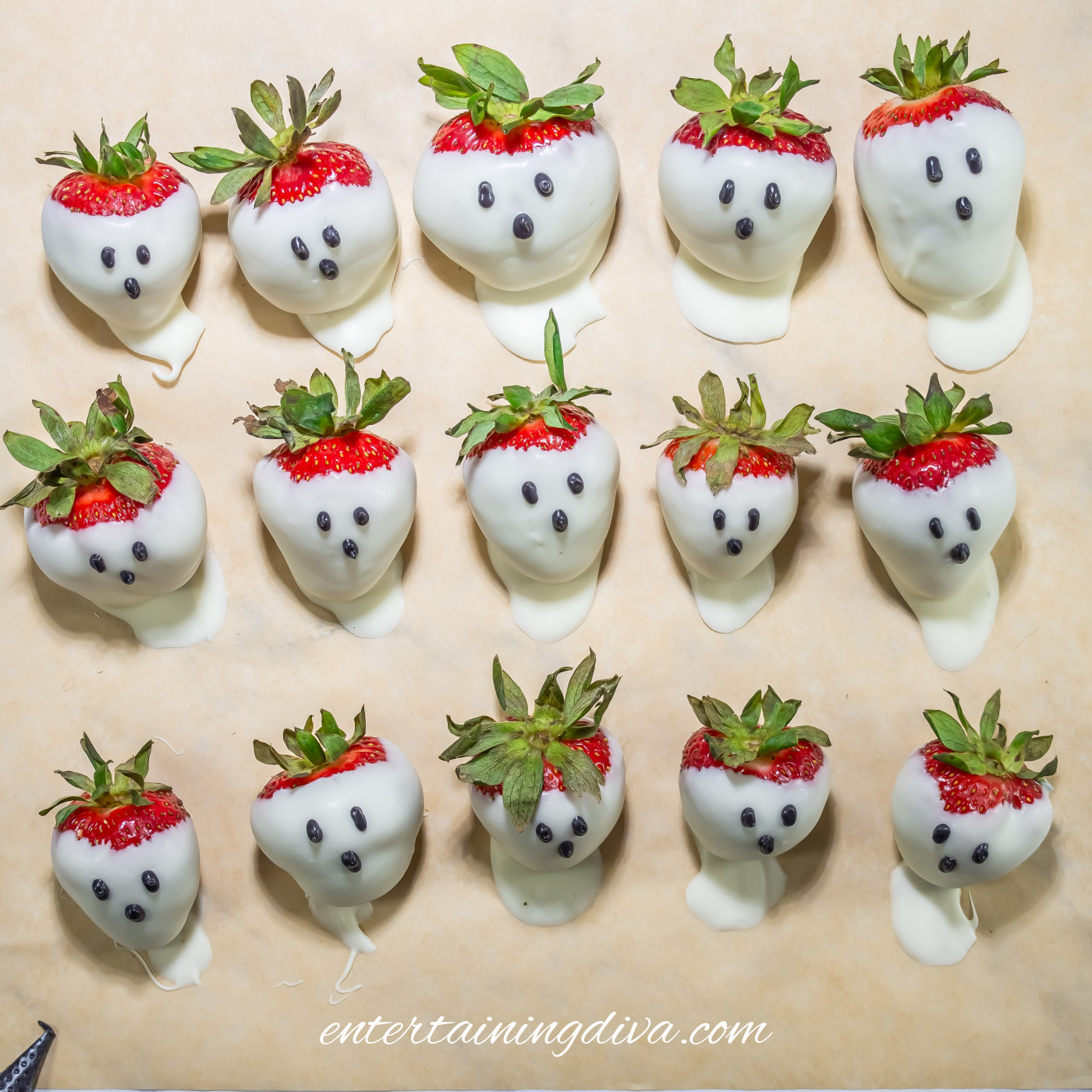 White chocolate-covered strawberries decorated with black ghost faces