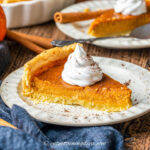 Close up of a slice of pumpkin pie with a dollop of whipped cream on top