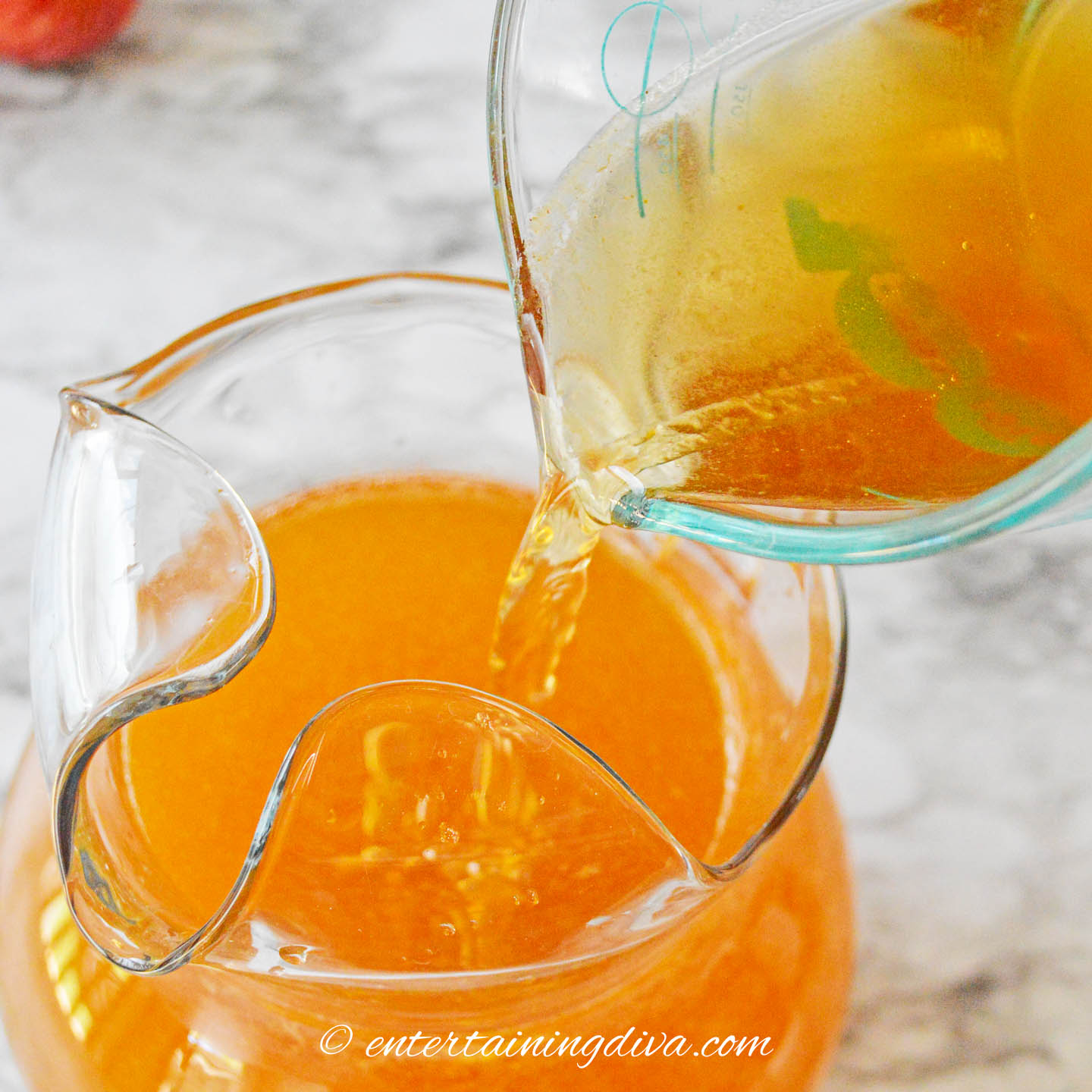 Spiced rum being poured into a pitcher of pumpkin sangria