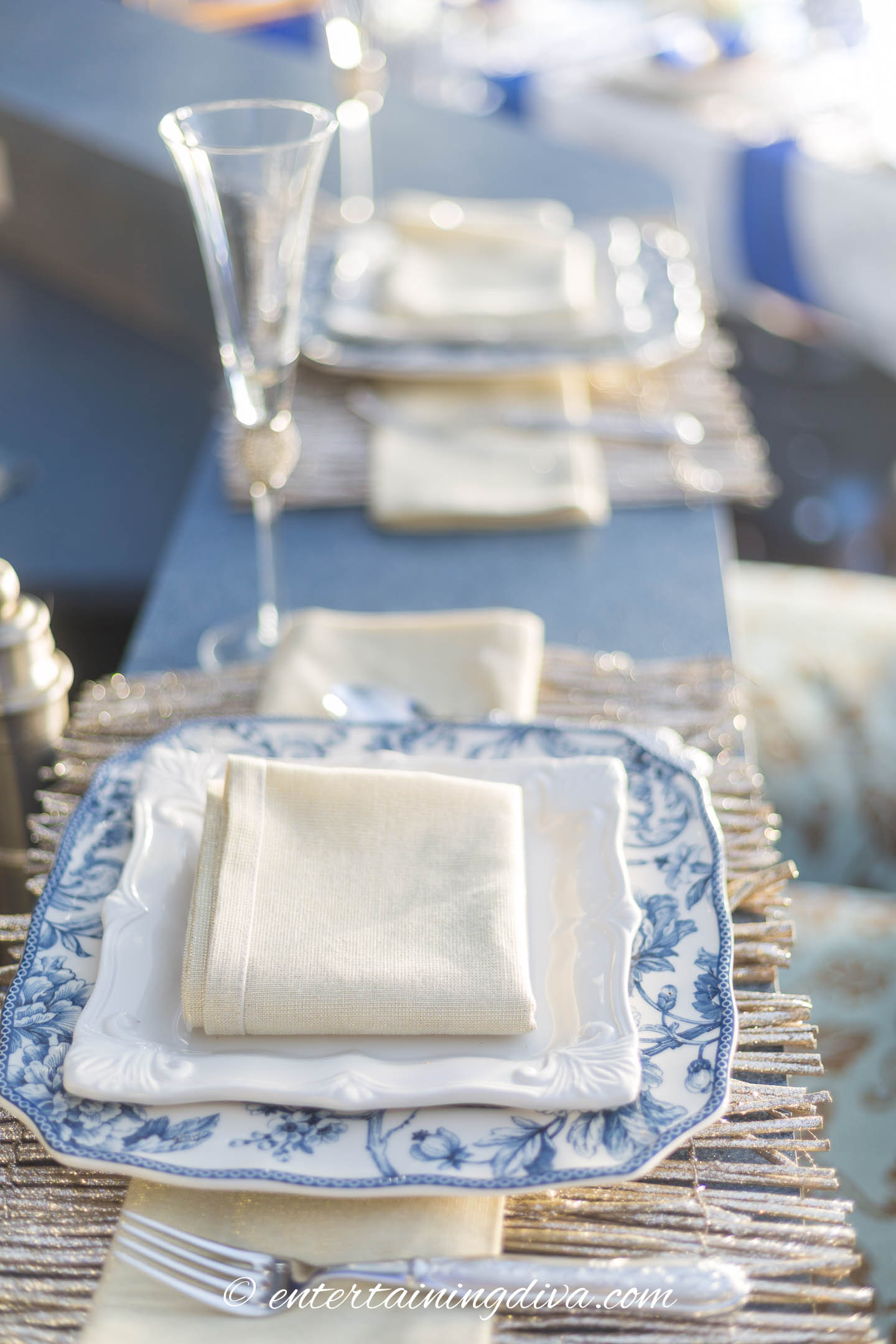A simple Christmas table setting with blue and white plates and gold place mats