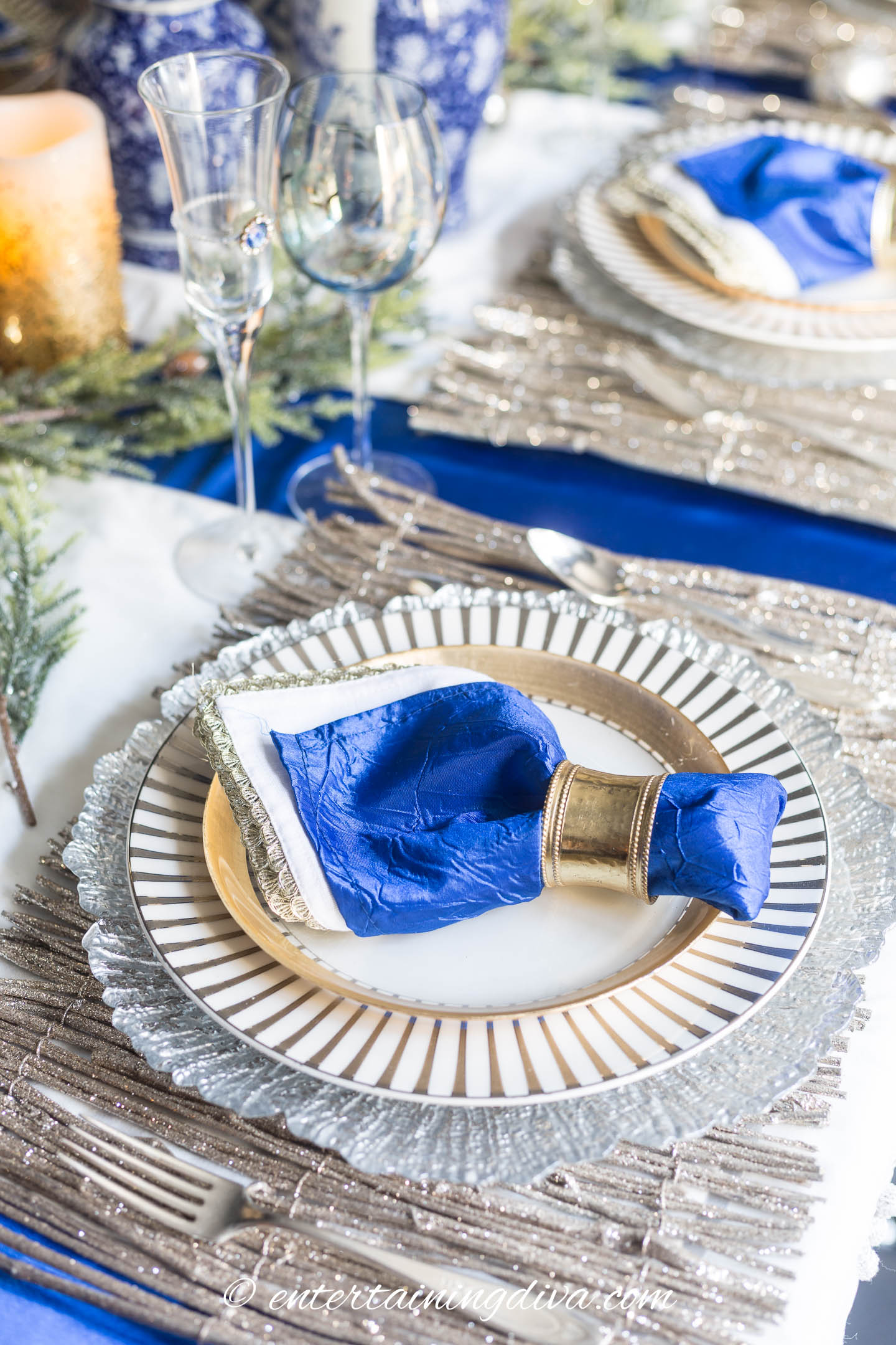 A blue, white and gold place setting with blue napkins, gold and white plates and gold placemats