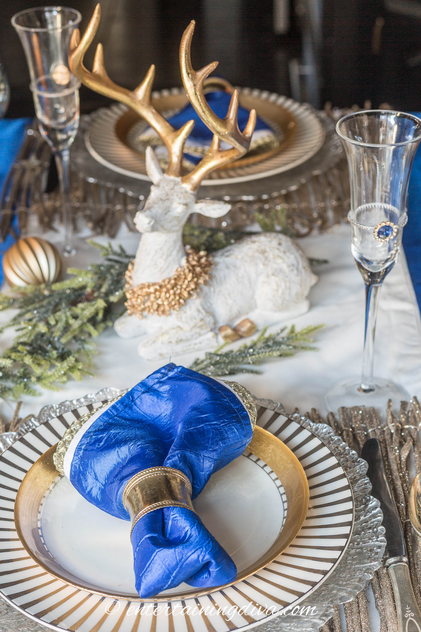 A white and gold deer decoration used as part of a centerpiece on a blue, white and gold Christmas tablescape