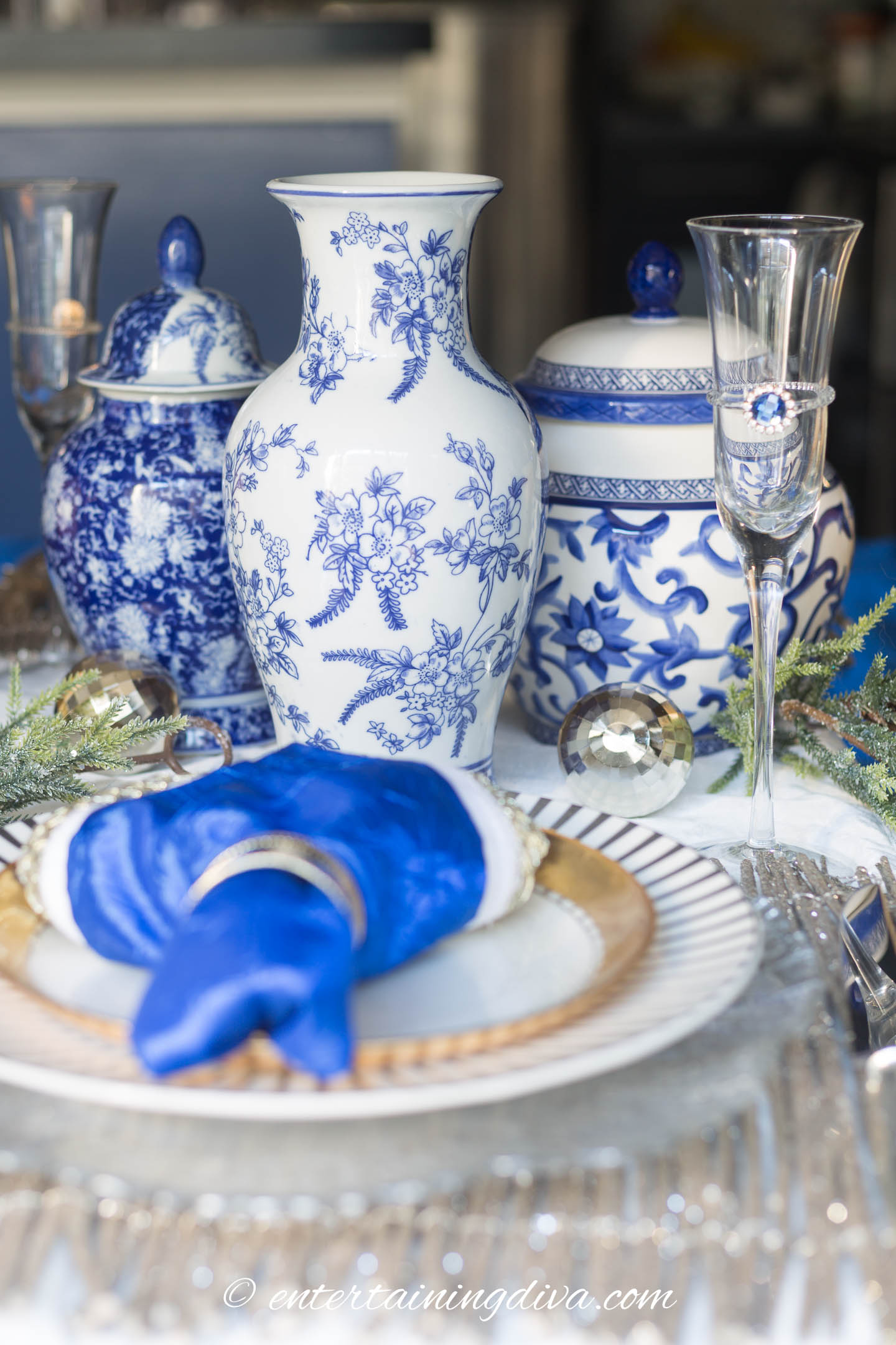 Blue and white ginger jars used as a centerpiece on a blue, white and gold Christmas table setting