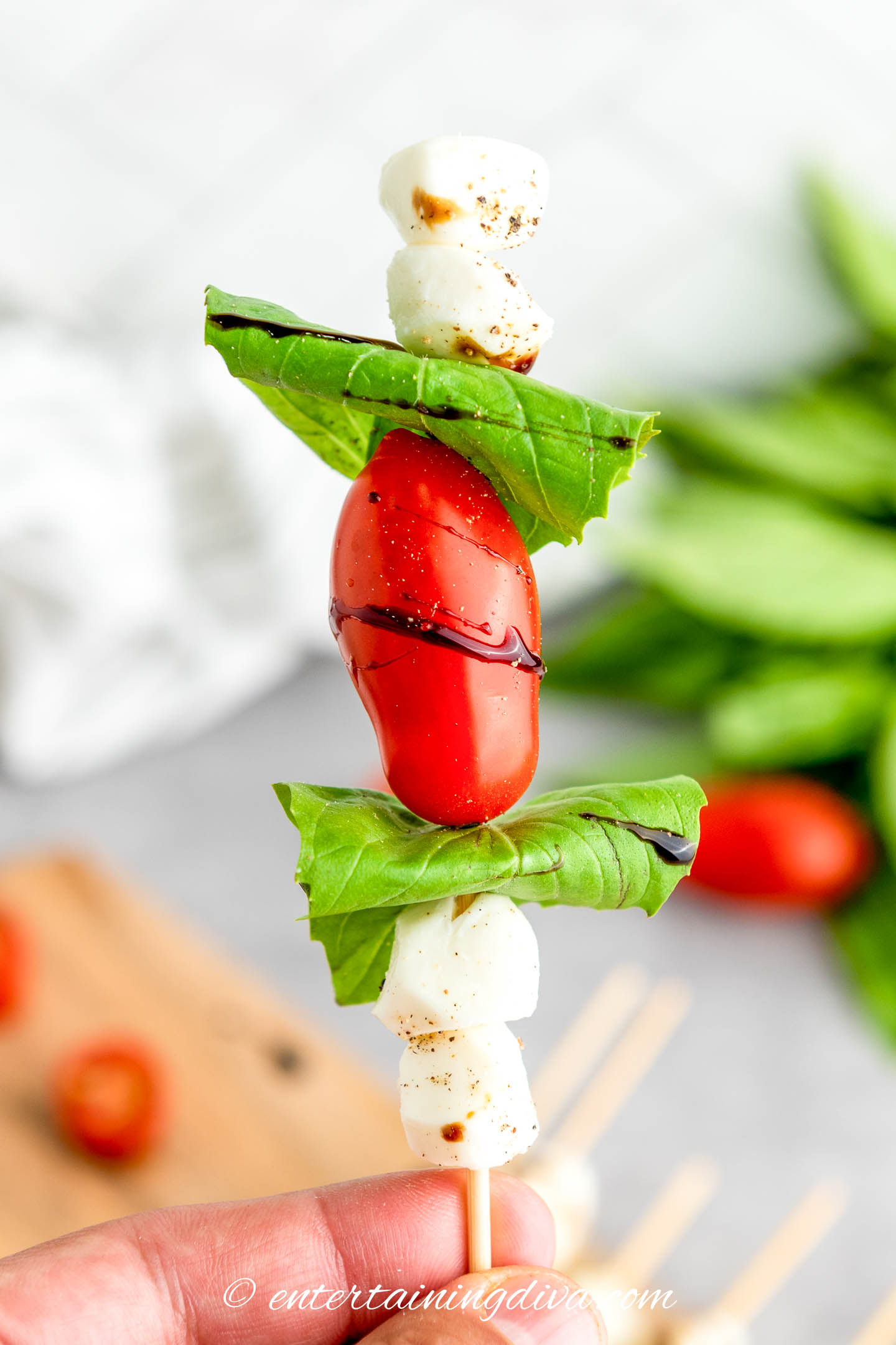 A single caprese skewer being held up by the skewer