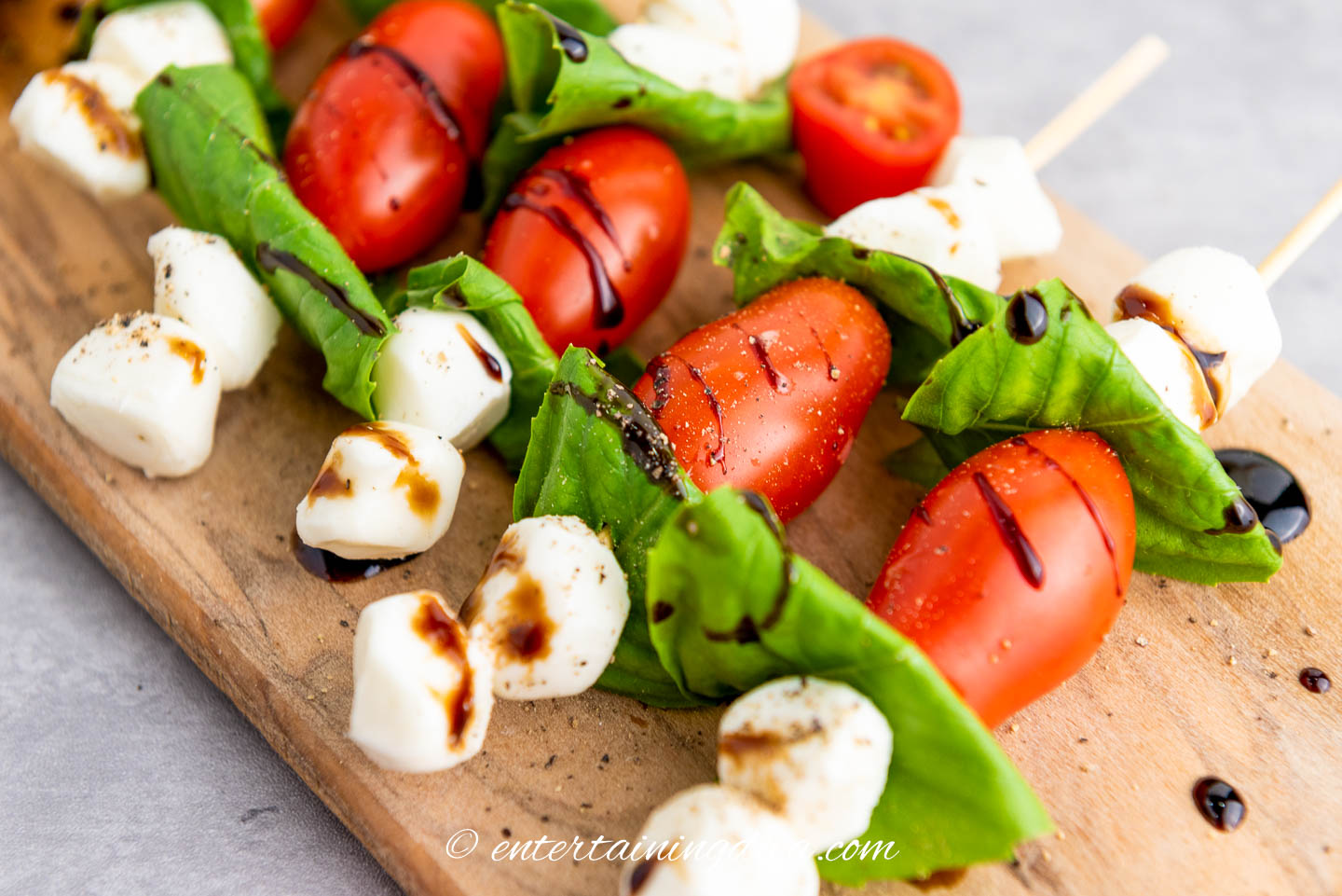 A close up of balsamic glaze drizzled on the caprese skewers along with some black pepper.