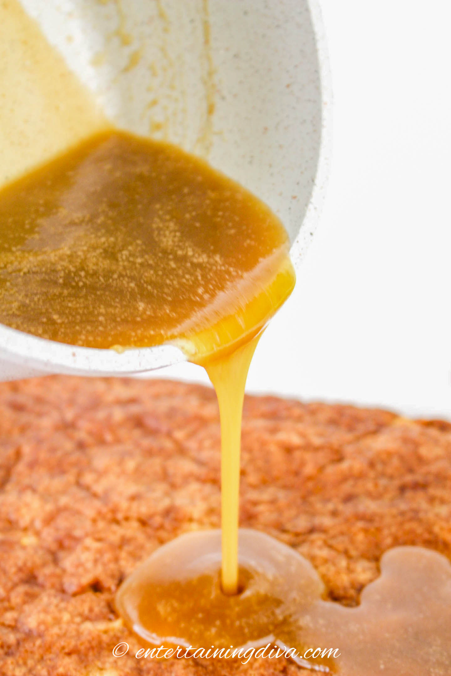 caramel sauce being poured over the apple sheet cake