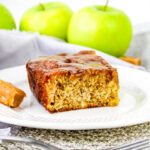 close up of a piece of caramel apple sheet cake on a plate in front of green apples