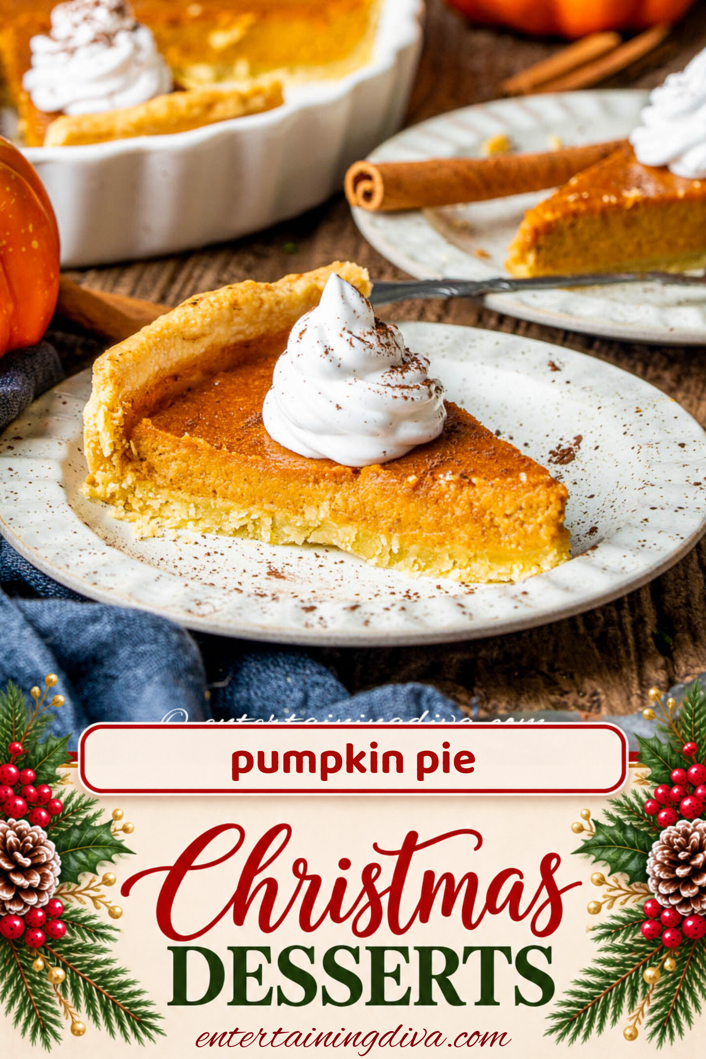 A slice of pumpkin pie topped with whipped cream on a plate, with a whole pie, pumpkin, and lantern in the background.