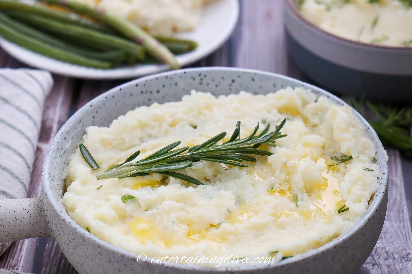 garlic mashed potatoes garnished with rosemary in a serving bowl