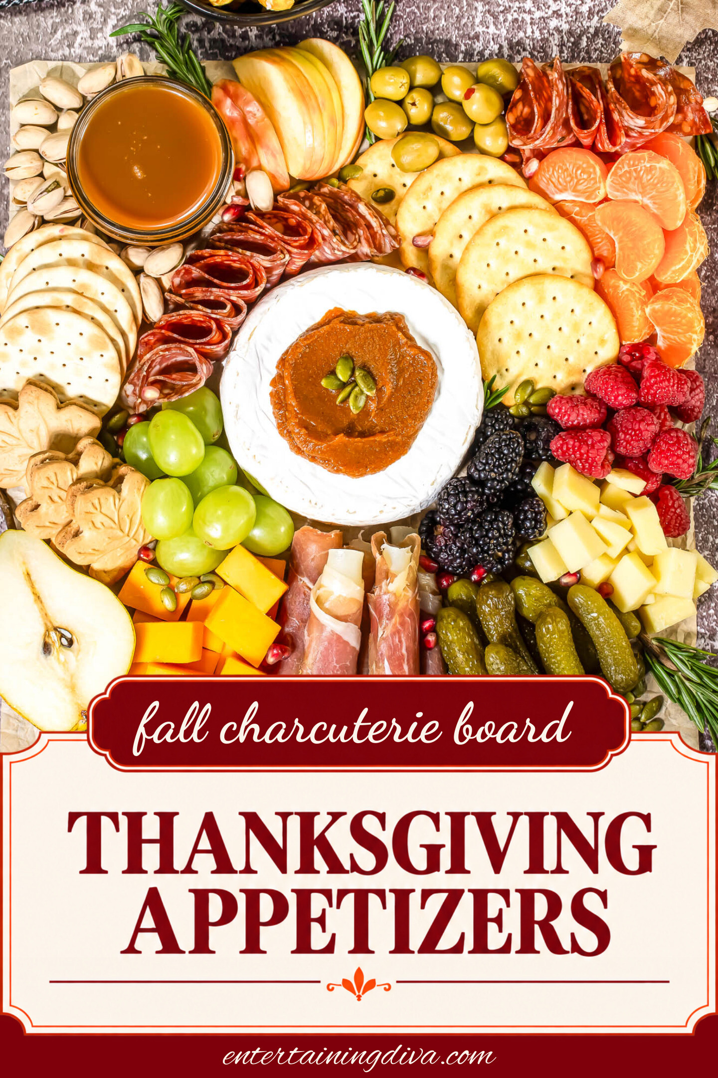 Charcuterie board with crackers, brie, cured meats, cheese cubes, pickles, fruit slices, berries, nuts, olives, and a bowl of dip, arranged neatly on a textured surface.