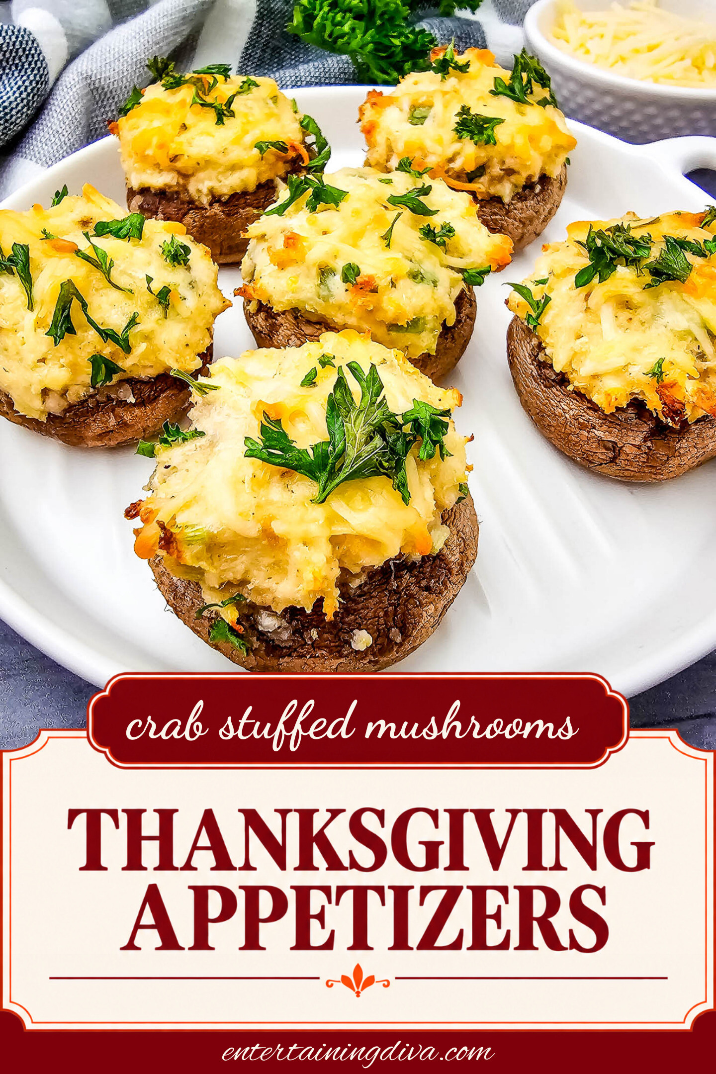 Five baked stuffed mushrooms topped with melted cheese and fresh parsley are arranged on a white plate, with a small bowl of grated cheese in the background.