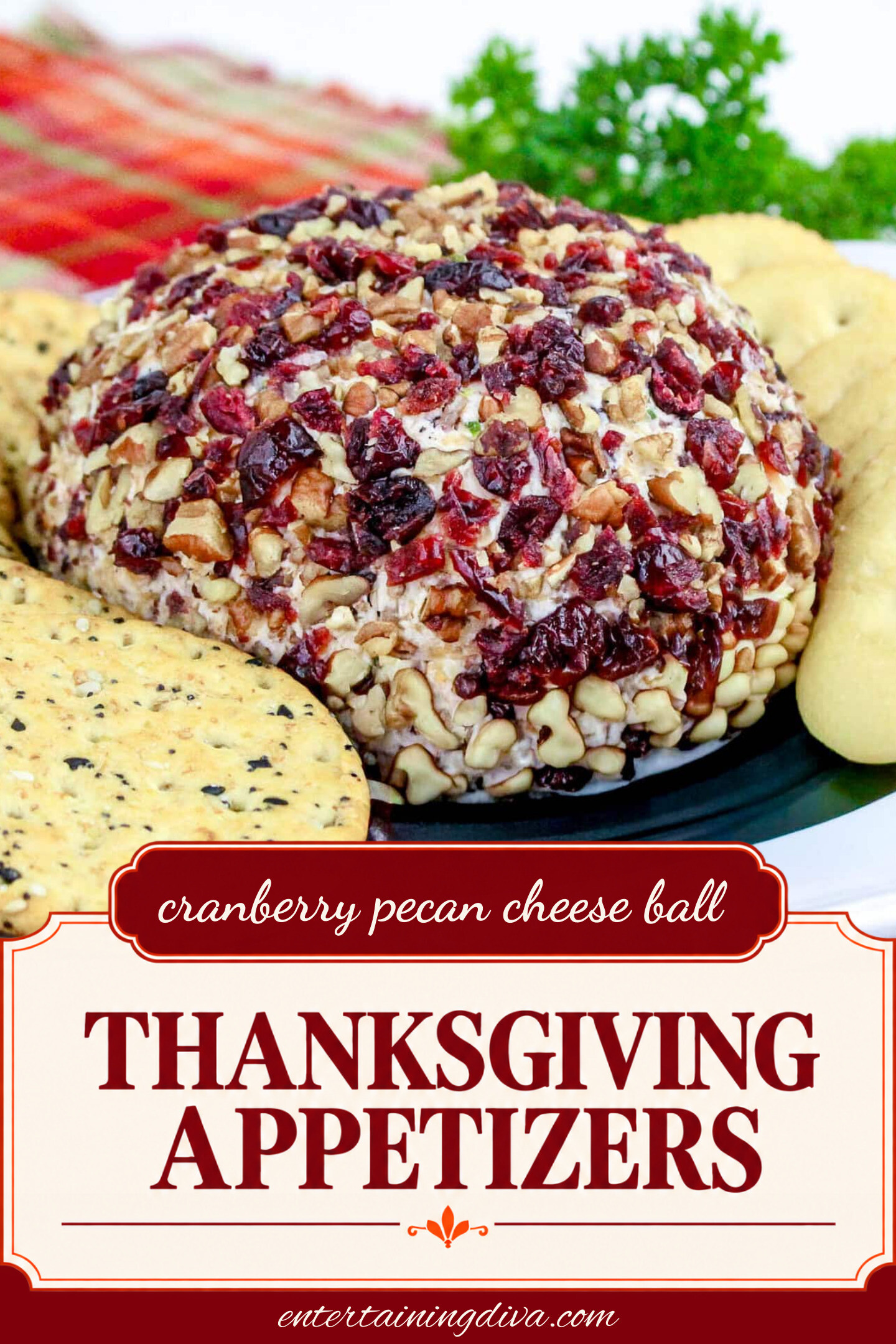 close up of cranberry pecan cheese ball on a plate with crackers
