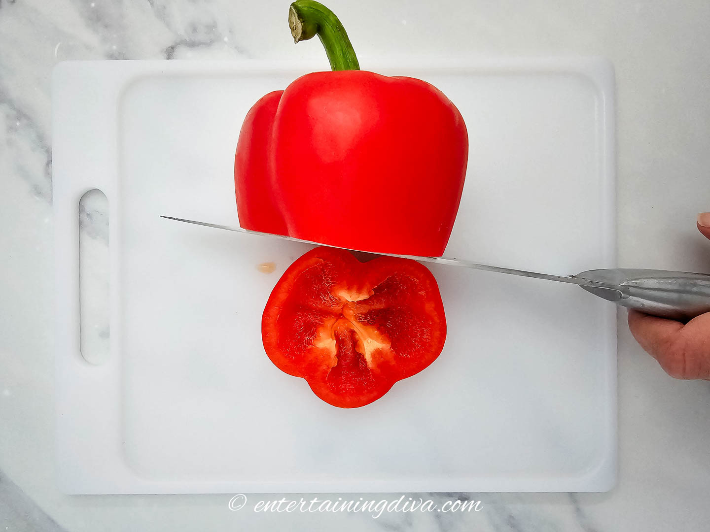 The bottom of a red pepper being cut off